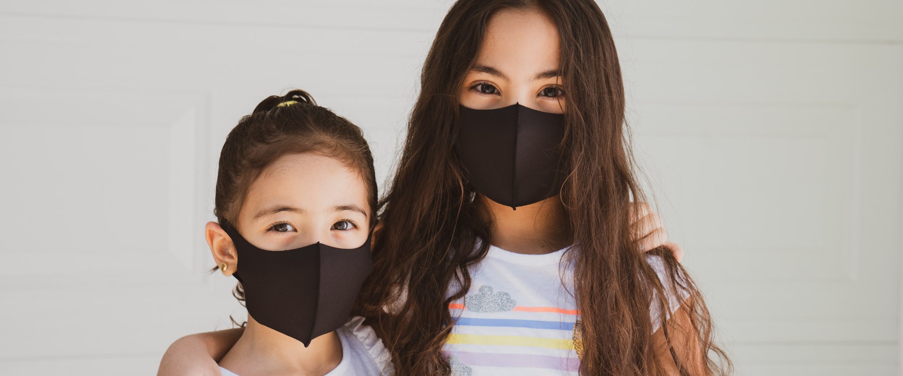 Two girls with mask looking happily side-by-side together