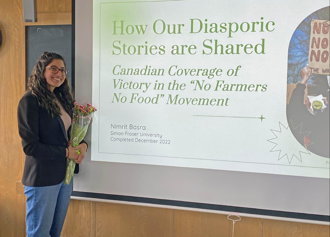 Nimrit Basra stands beside a slide from her honours presentation