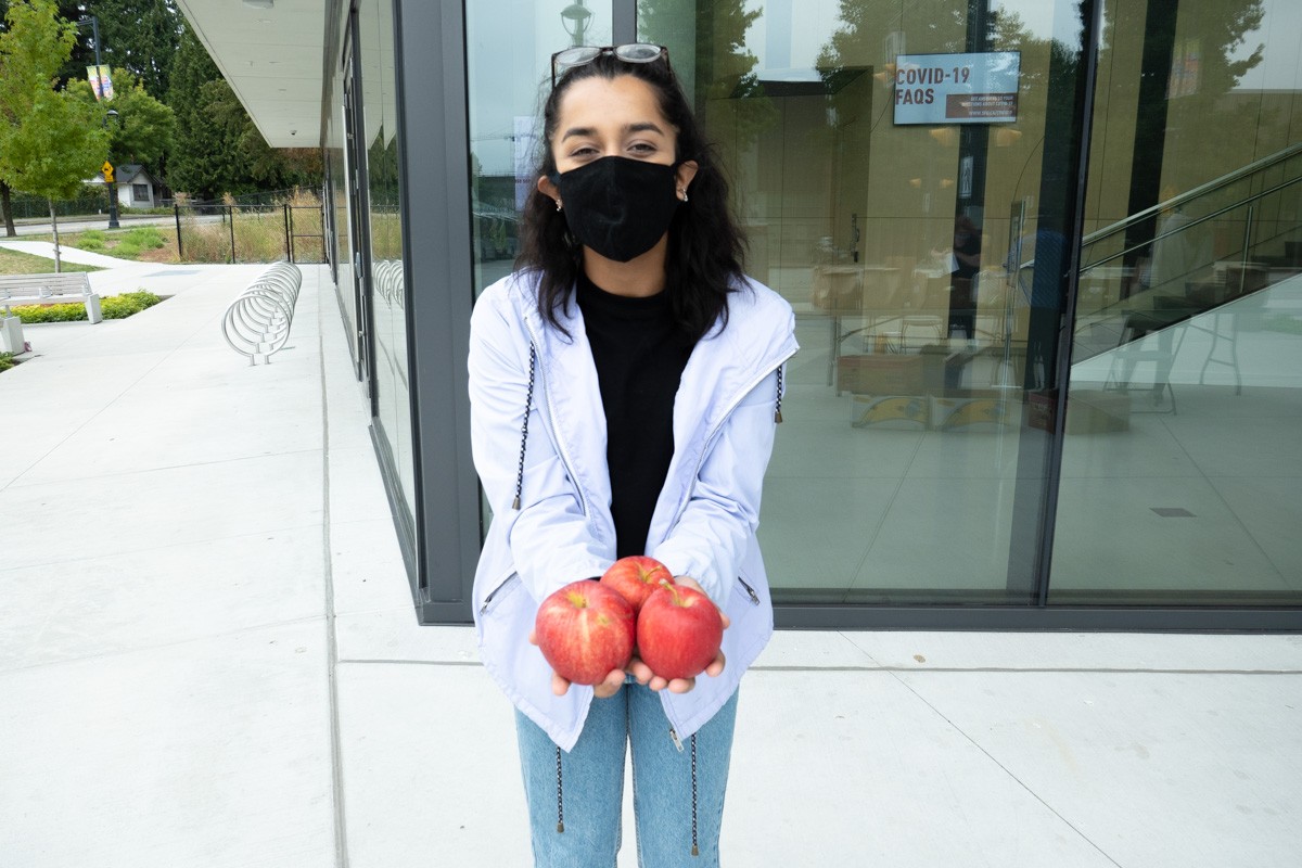 Surbhi Ratti at the Farms to Campus initiative holding apples in her hand.