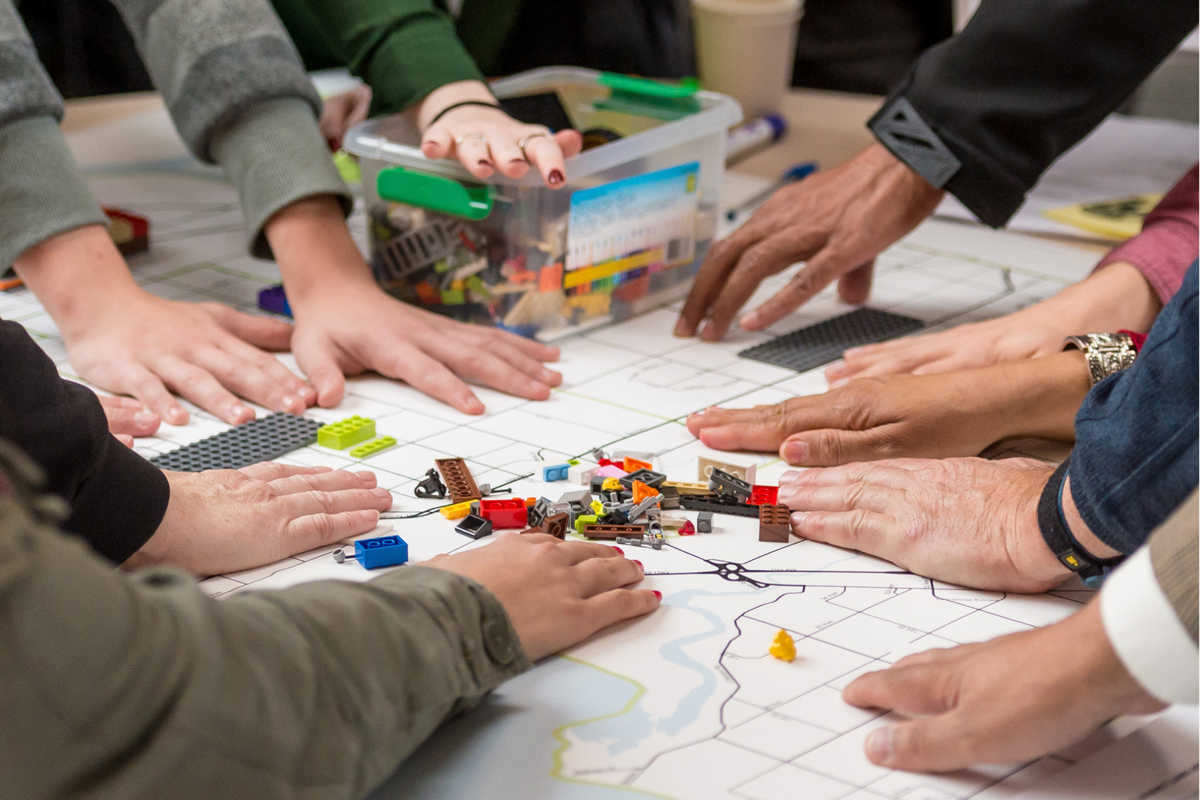 A bunch of hands assembling legos in a team-building exercise