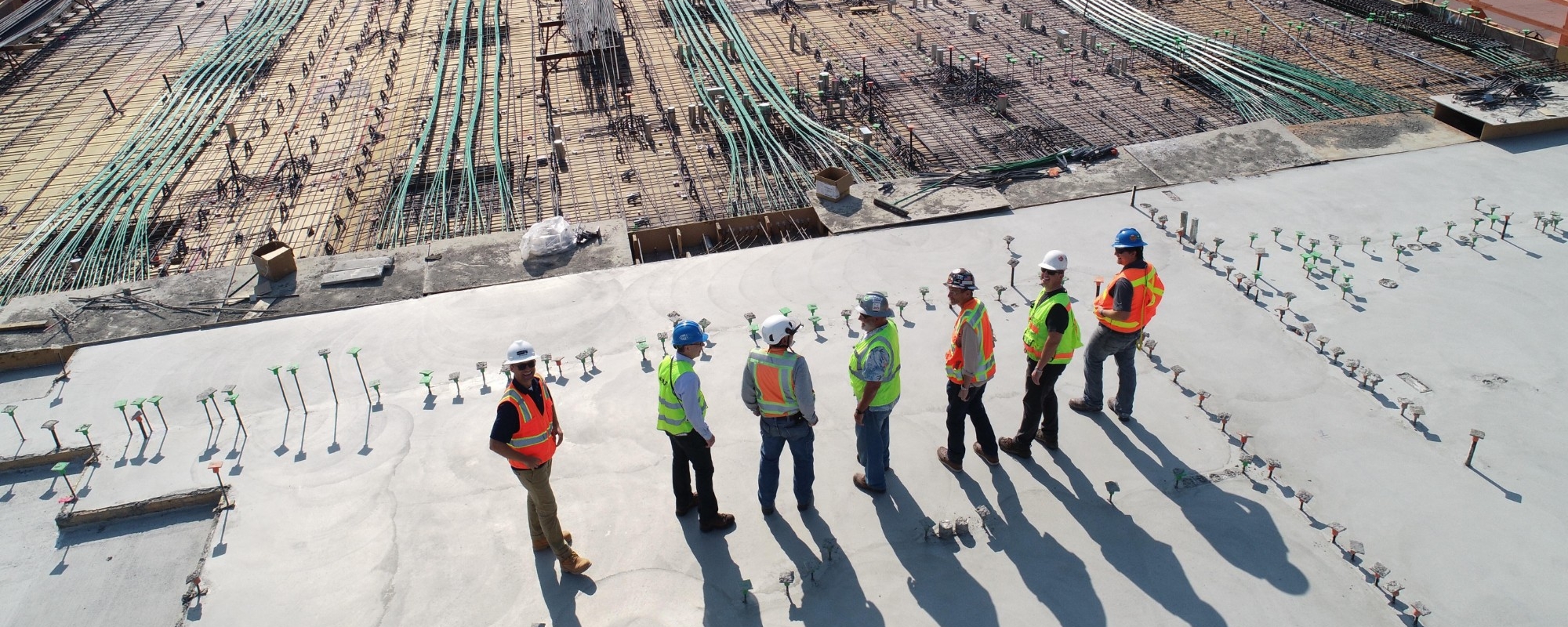 Seven construction workers standing on concrete rooftop