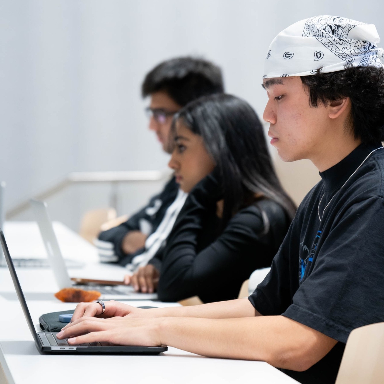 Three students taking notes on their laptops during a lecture in SFU Surrey.