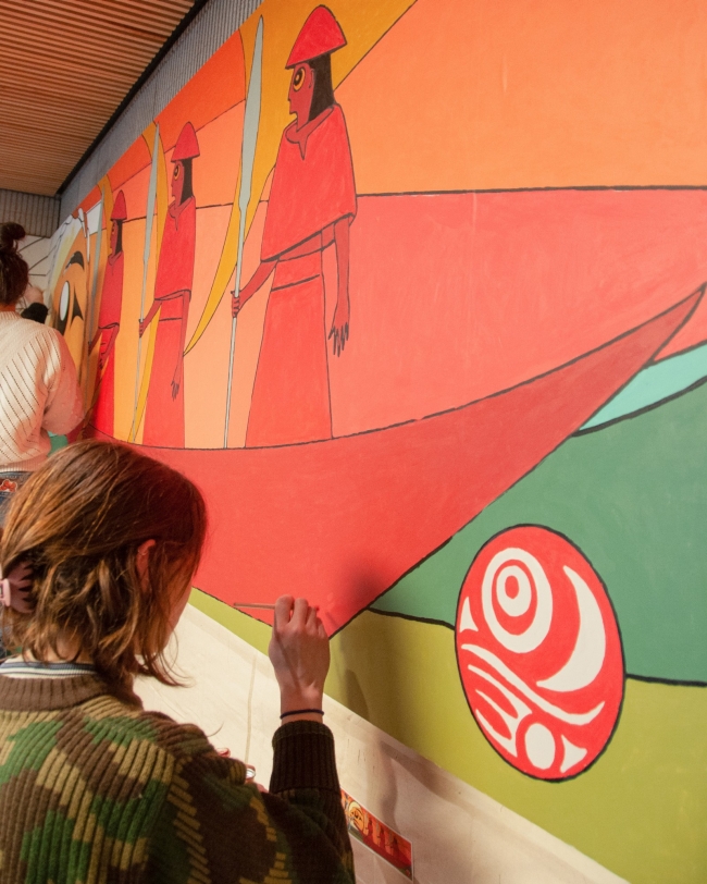 Student painting a section of the mural