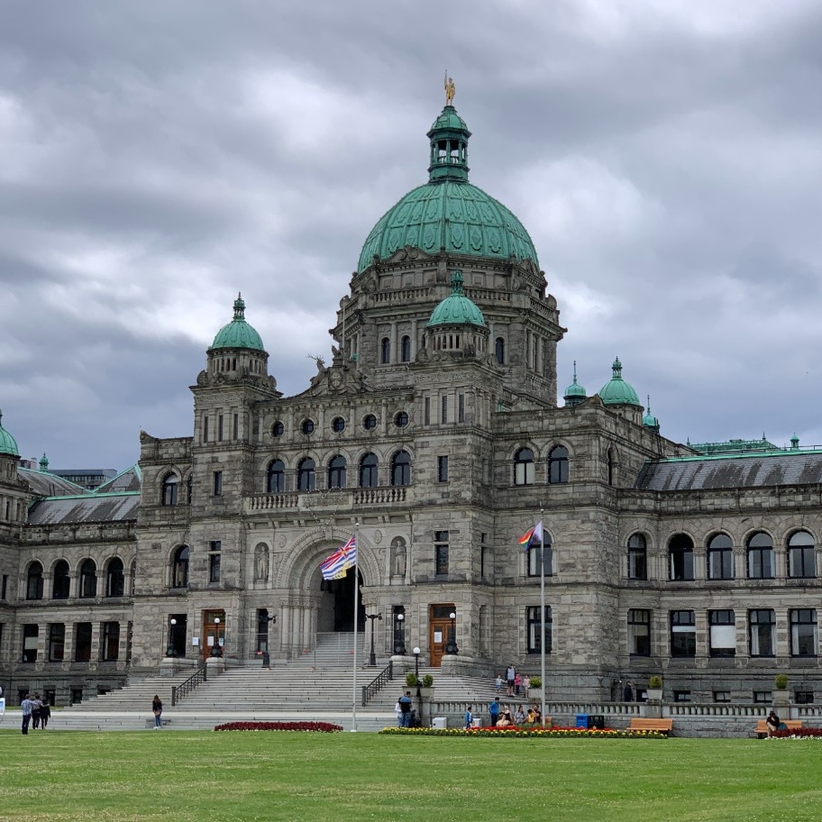 A photograph of the Parliament House in Victoria, British Columbia, underneath grey clouds in the late afternoon. 