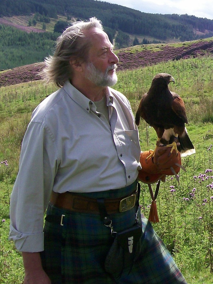 Picture of (William) Rex Davidson outside wearing a kilt and shirt with a bird on his arm