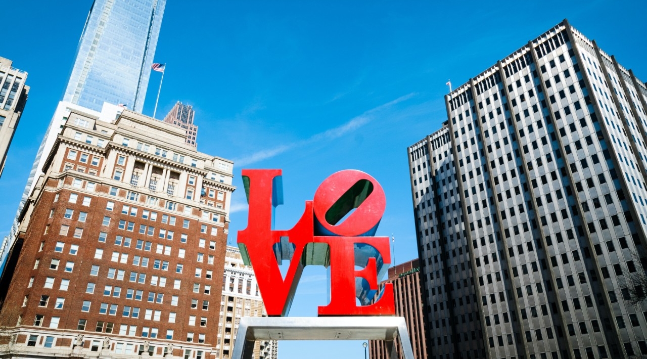 The letters L-O-V-E are silhouetted against a bright blue sky.