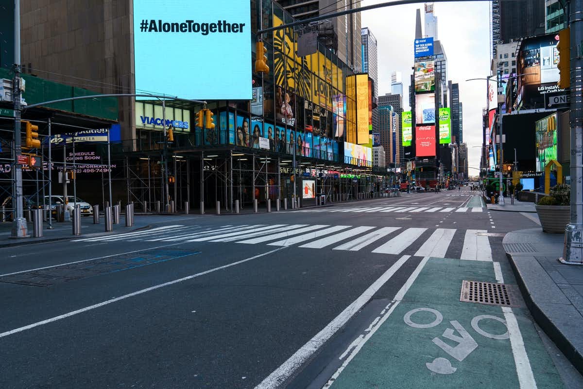 A billboard that says #AloneTogether shines above an empty New York City street.
