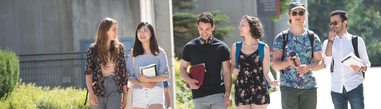 SFU residents walking outside residence towers while conversing and smiling.