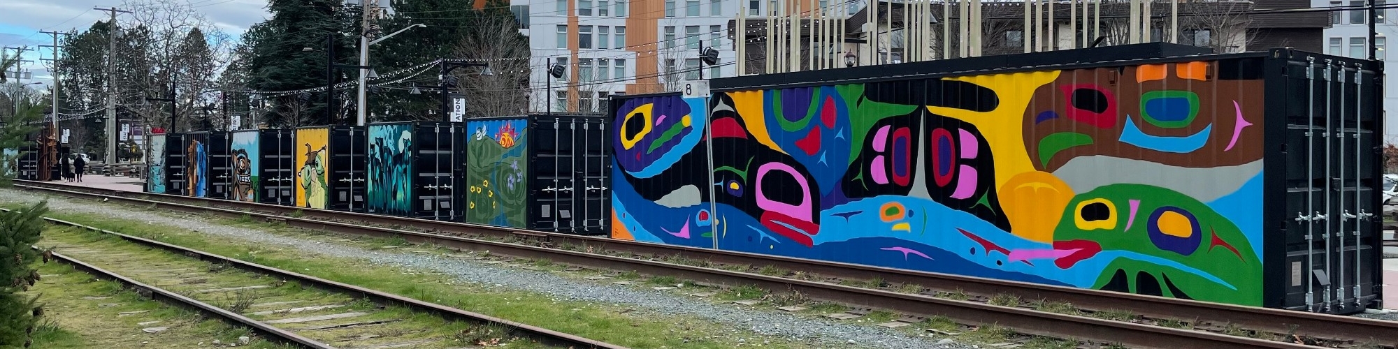 train tracks and Indigenous mural in Langford, Victoria B.C. as background for Contact page