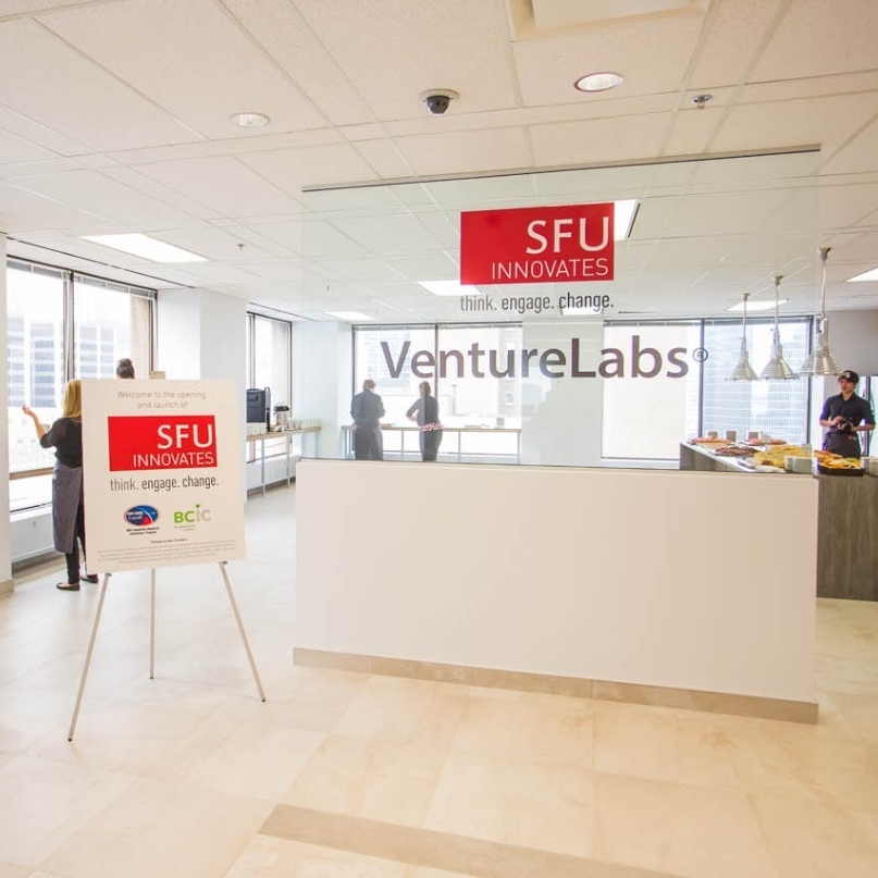 Front entrance to VentureLabs® office space with people standing in one the office's common areas and kitchen