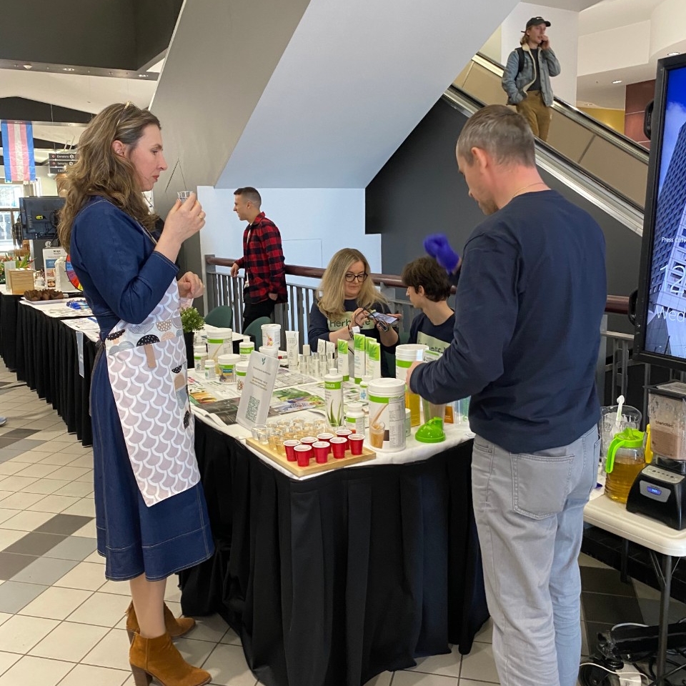 Two people talking and sampling smoothies at a table at the Wellness Fair, as part of 2023 Wellness Days event