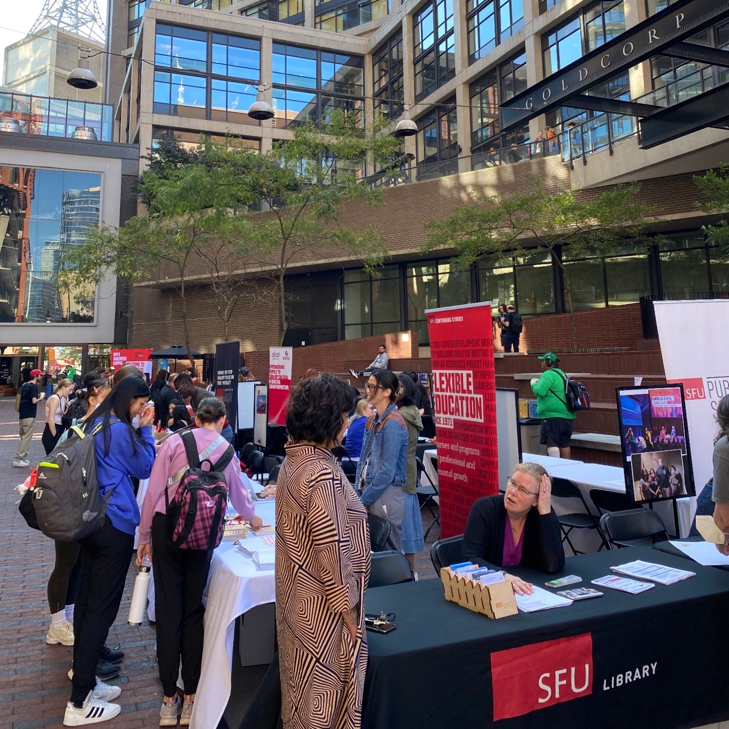 Vendors set up outdoors with multiple people visiting the various vendors' tables as part of 2023 SFU Vancouver Welcome Back BBQ