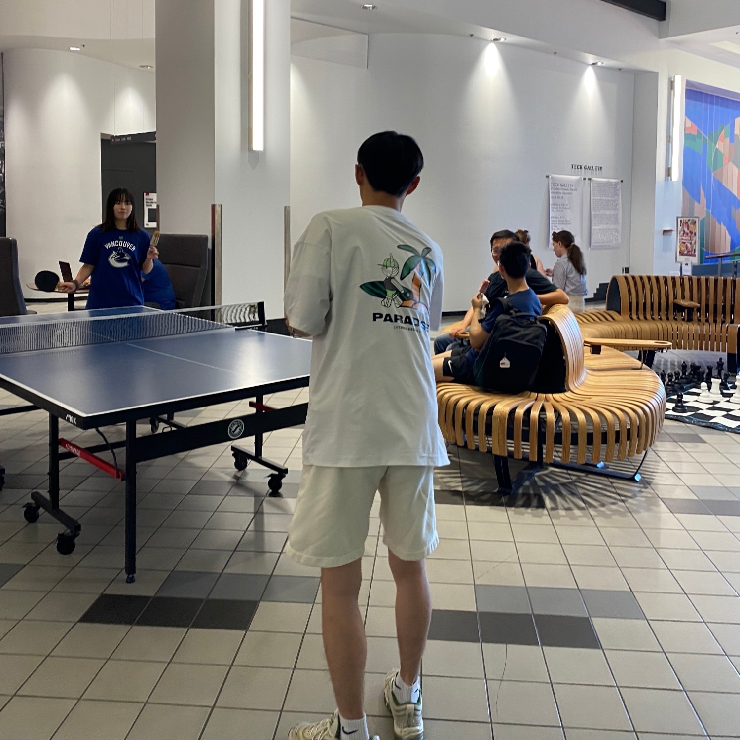 People enjoying popsicles and playing ping pong in the Games Lounge, with people sitting on benches nearby, at the 2023 Summer Social