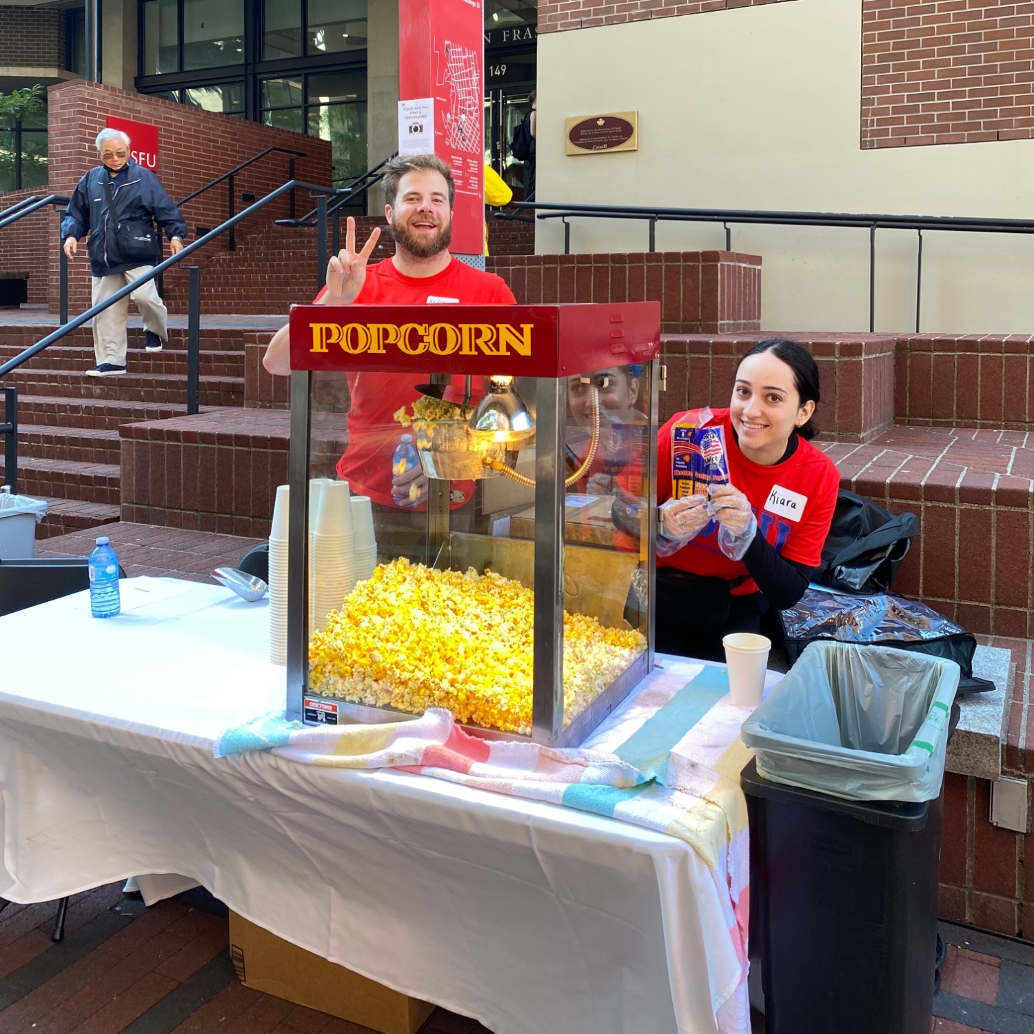 Two staff volunteers at the popcorn machine at 2023 Welcome Back Community BBQ