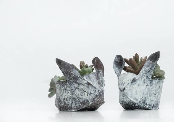 Two small orgami bunny shaped plant holders with succulents in it.