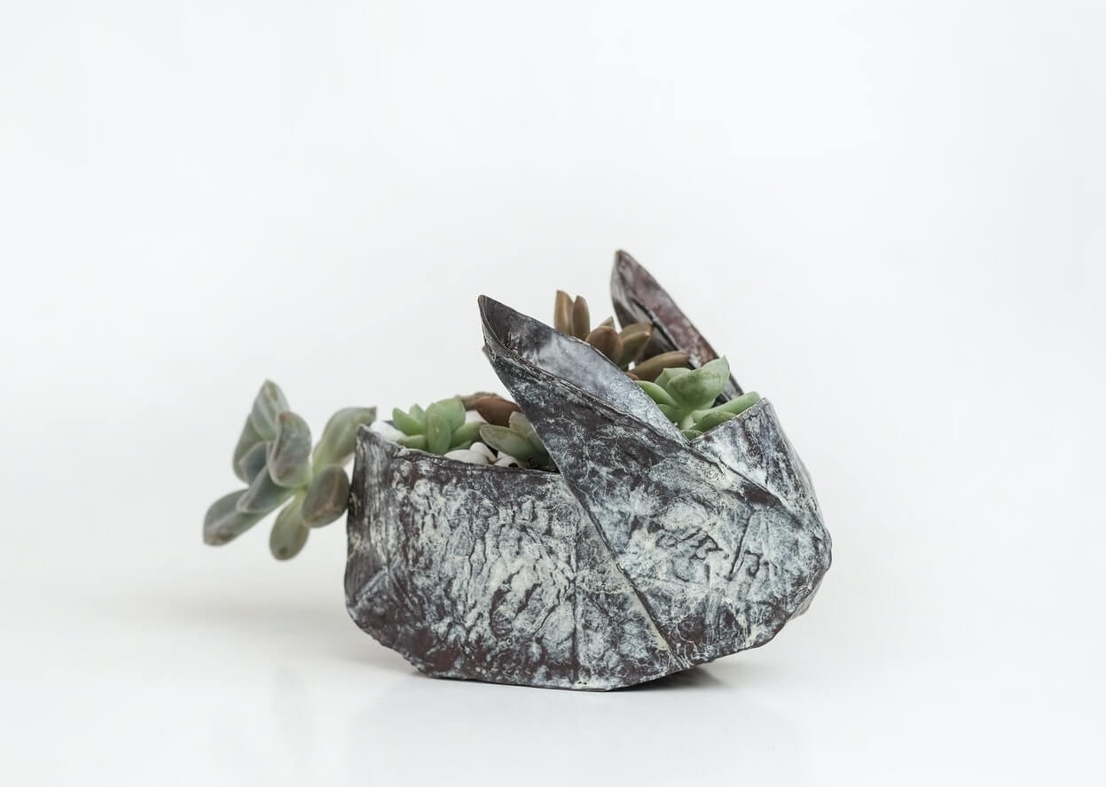 A small single origami bunny shaped plant holders with succulents in it.