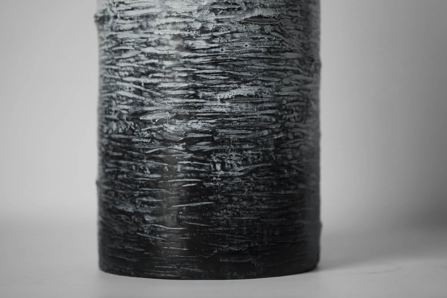The bottom of a textured cylindrical vase with a white gradient from the top transitioning to black.