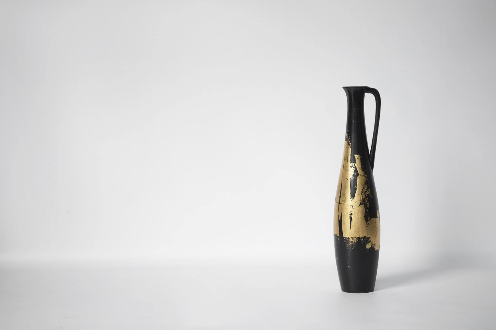 A black vase with a gold patina.