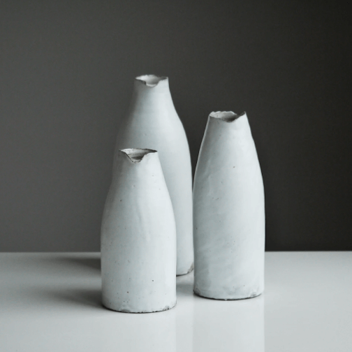 three white ceramic bottles with varying heights.