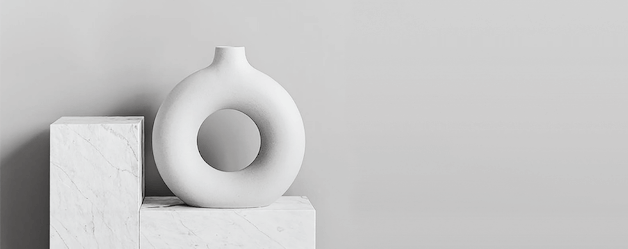 a circle shaped vase on a marble stand.