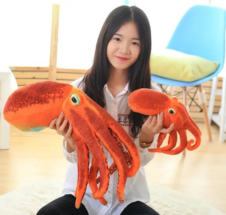 A white dressed girl holding two orange octopus stuffed toy on each hand