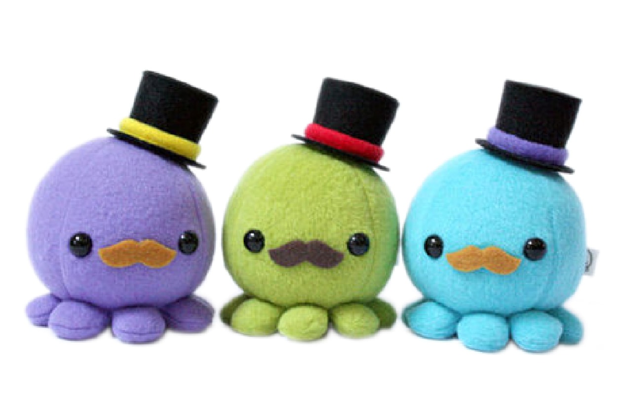 Three uniquely coloured octopus plush each with moustaches and a top hat