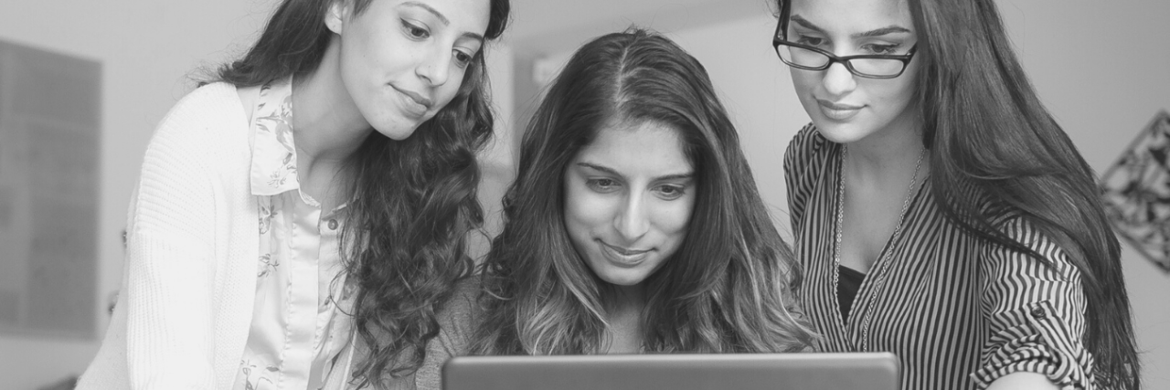 three women looking at computer