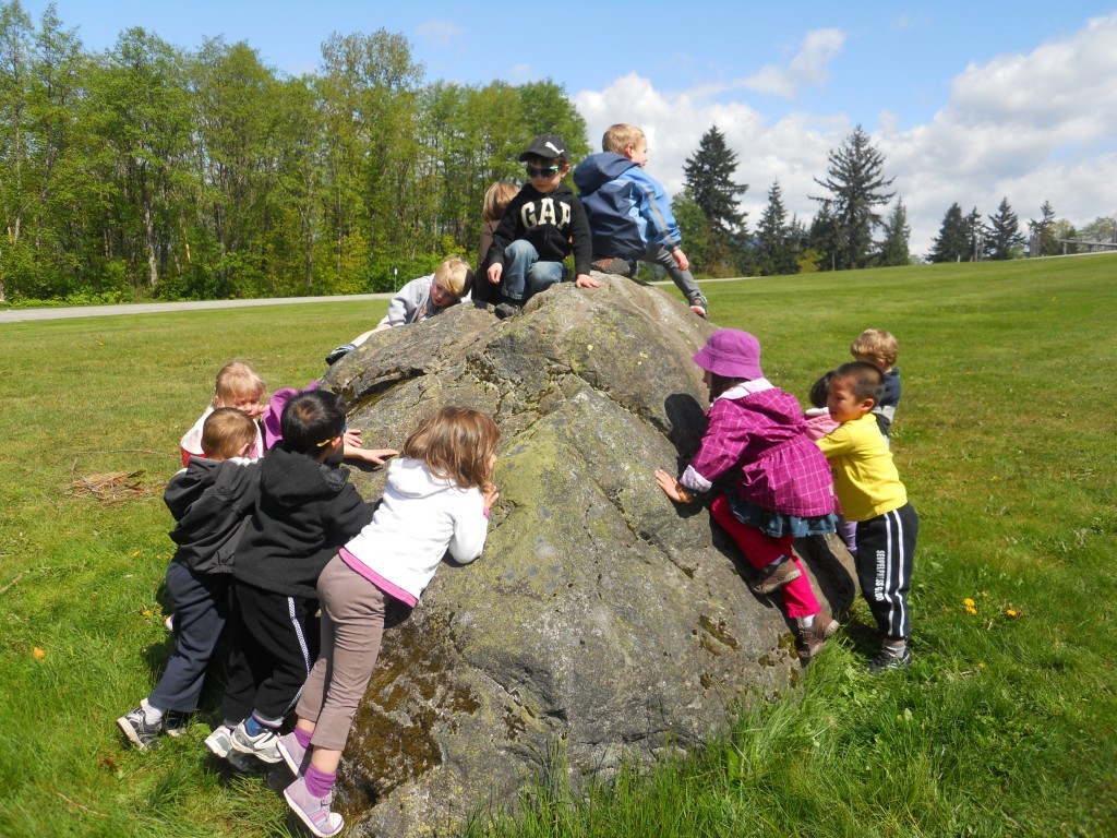 A group of children climbing a large rock