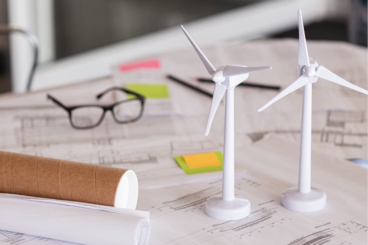 Model windmills on a table with paperwork and a pair of glasses