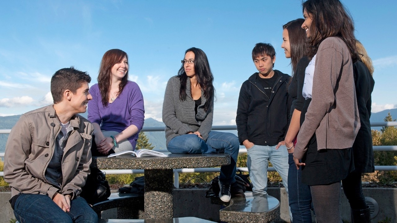 Six students standing around a concrete picnic table at SFU's Burnaby campus 