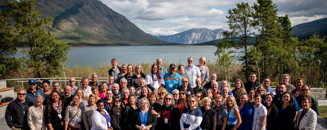 Group picture of the Summer Institute participants outside in front of a lake and mountains