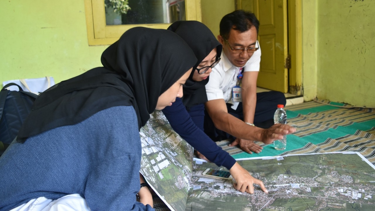 Semarang, Indonesia: Three people from Kota Kita standing around a map. One person is pointing at an unidentified spot on the map.