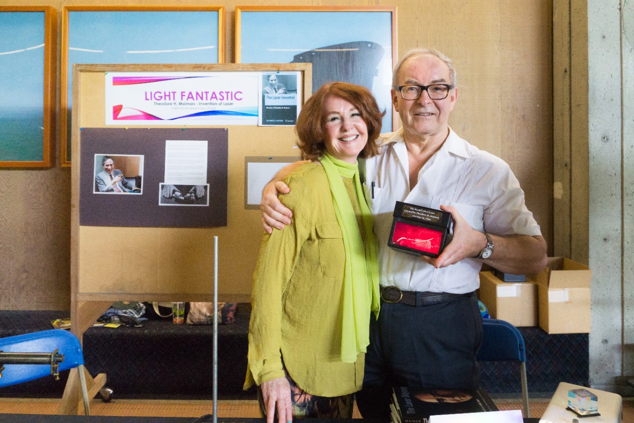 Kathleen Maiman with SFU engineering science professor Andrew Rawicz, holding a hologram of the first laser at a science outreach event.