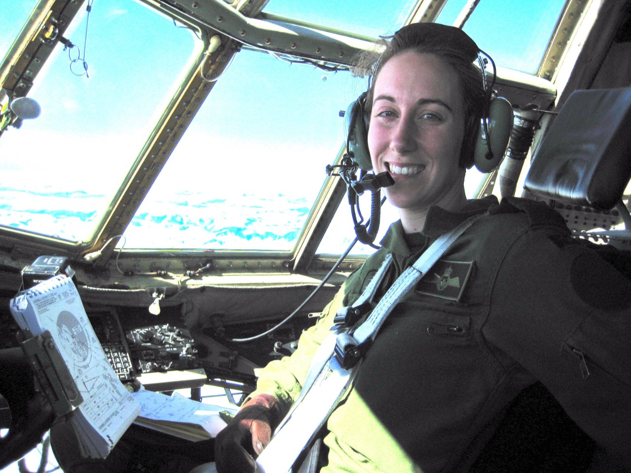 Kathryn Nurse, a female military pilot, smiles at the camera from the inside of a plane's cockpit
