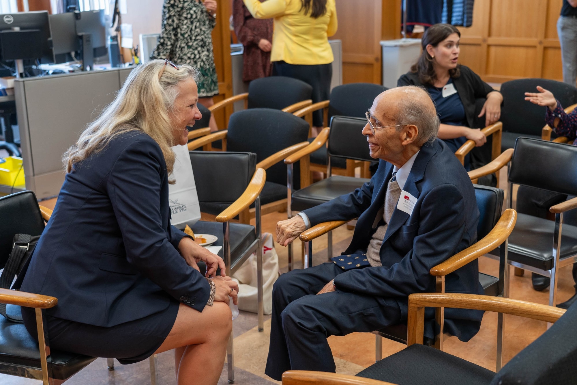 Laurel Weldon is candidly photographed next to Dr. A.H. Somjee. She is laughing and he is smiling at her in the photograph.