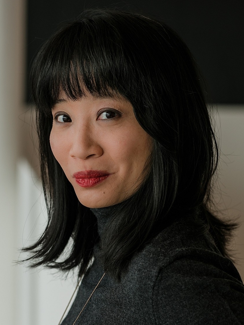 Portrait of Joanne smiling at the camera. She has short black hair and is wearing red lipstick.