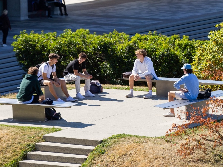 Students sitting outside in the Academic Quadrangle (AQ)