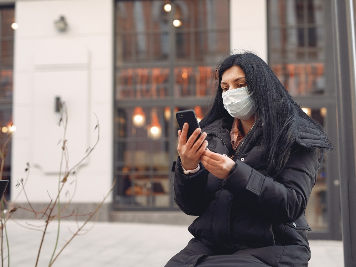 Woman in a mask sitting on the street