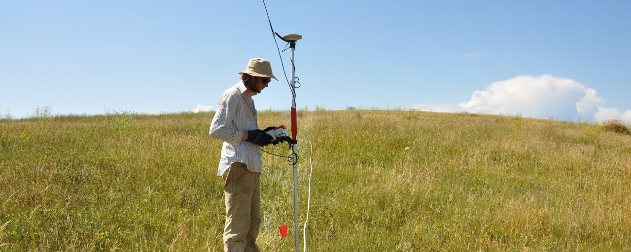 side profile image grad student using geophysical equipment in the field