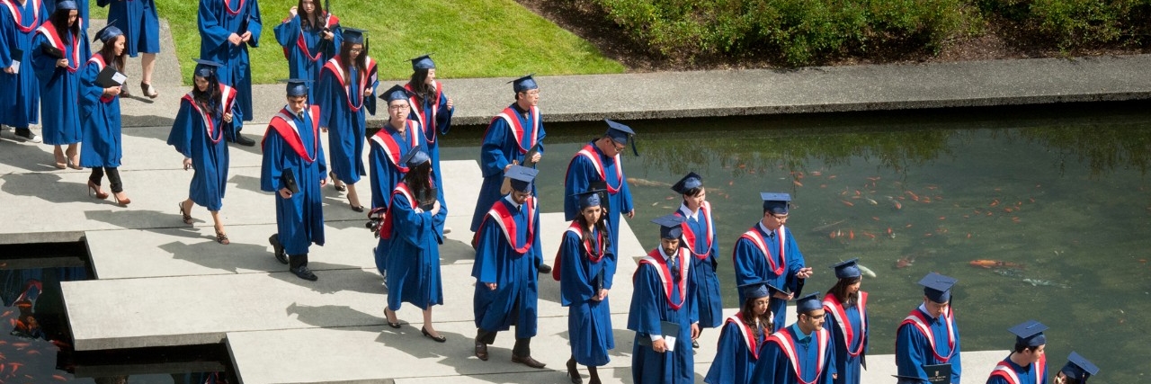 SFU graduates in regalia crossing the AQ pond on their way to the convocation ceremony