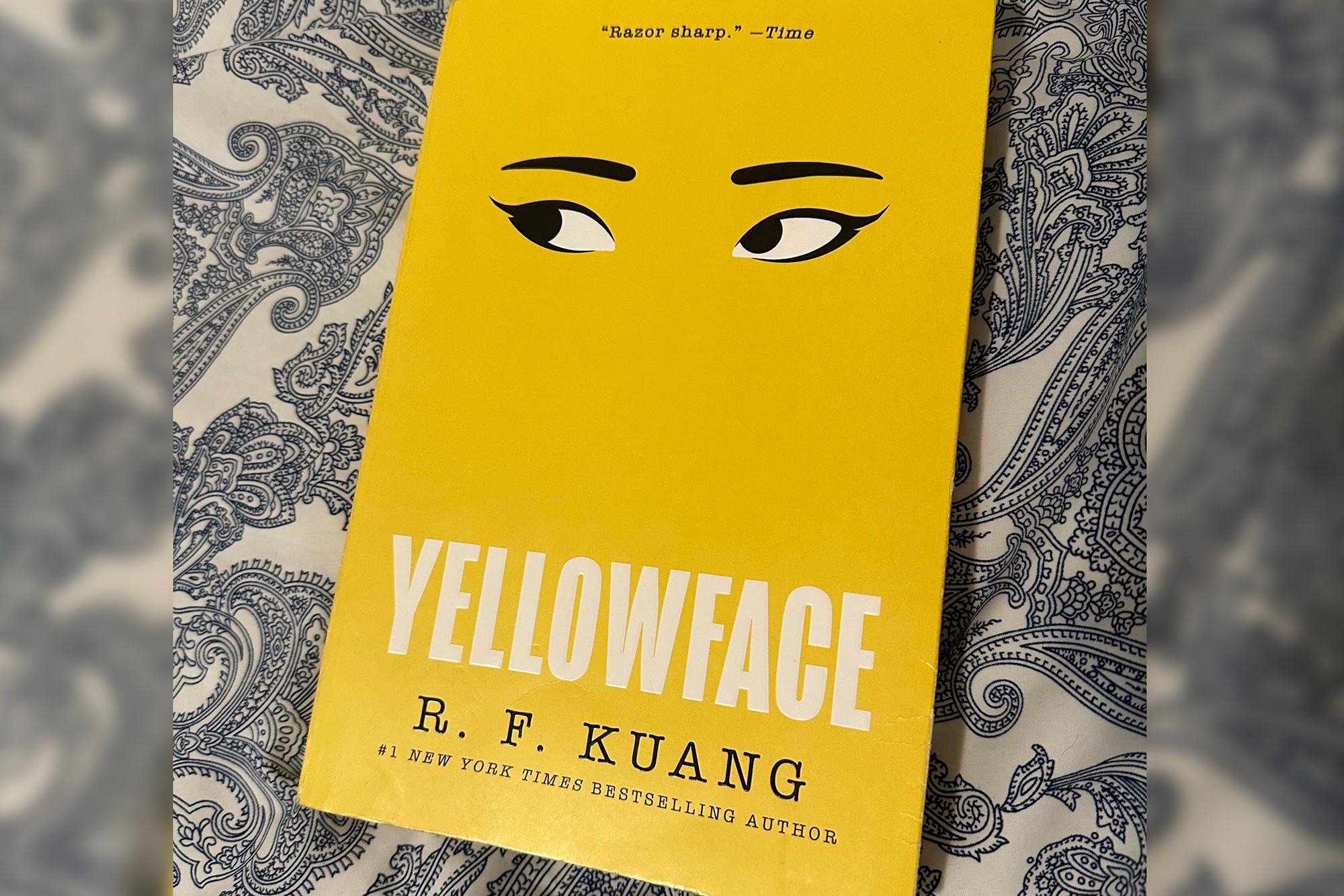 A copy of Yellowface by R. F. Kuang on a patterned cloth