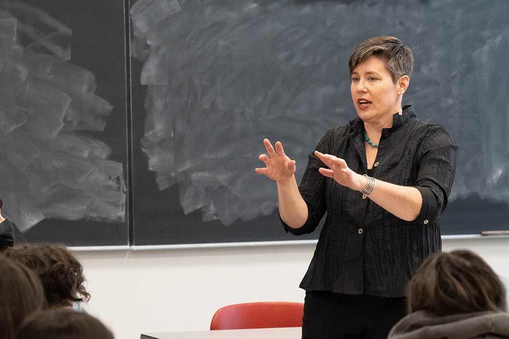 Tiffany Muller Myrdahl teaching in a classroom, standing in front of a blackboard