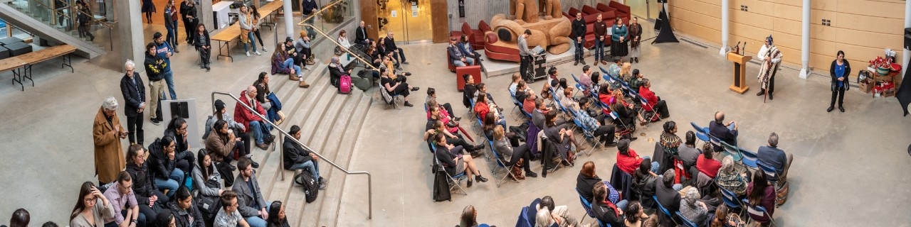 A crowd seated in chairs at an event in Saywell Atrium