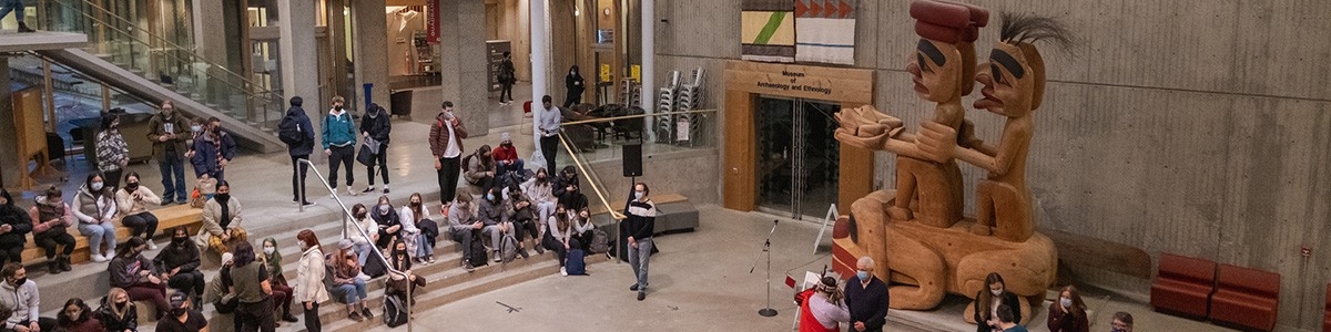 A crowd sitting on the steps and event seating in Saywell Hall Atrium
