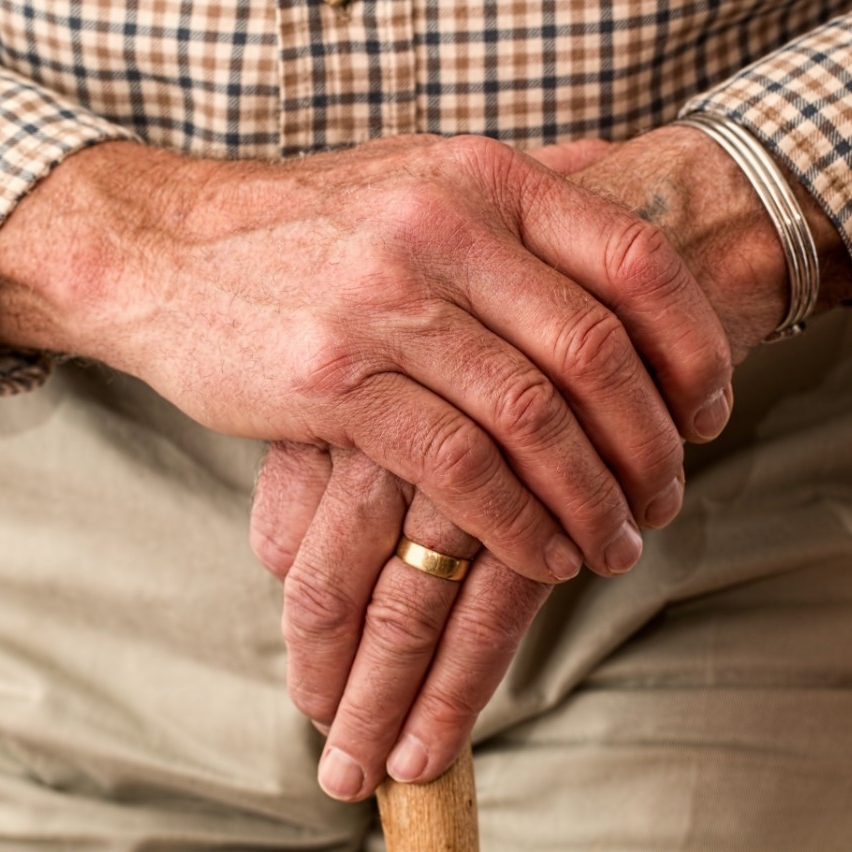 An elderly man's hands resting on cane