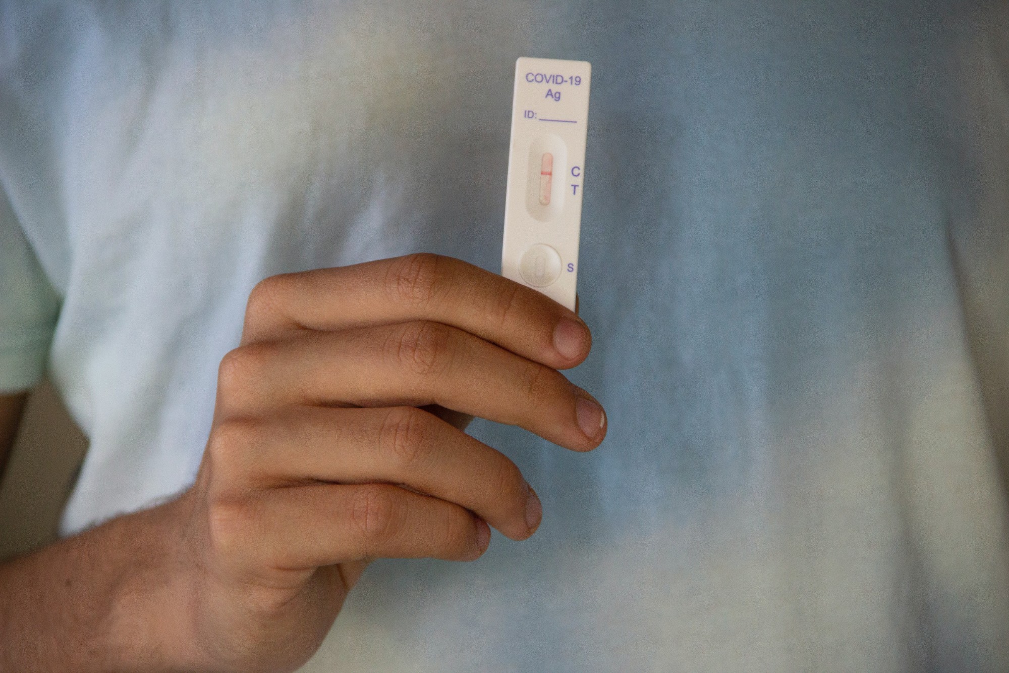 Close up of a person holding up a white covid-19 rapid test against their shirt