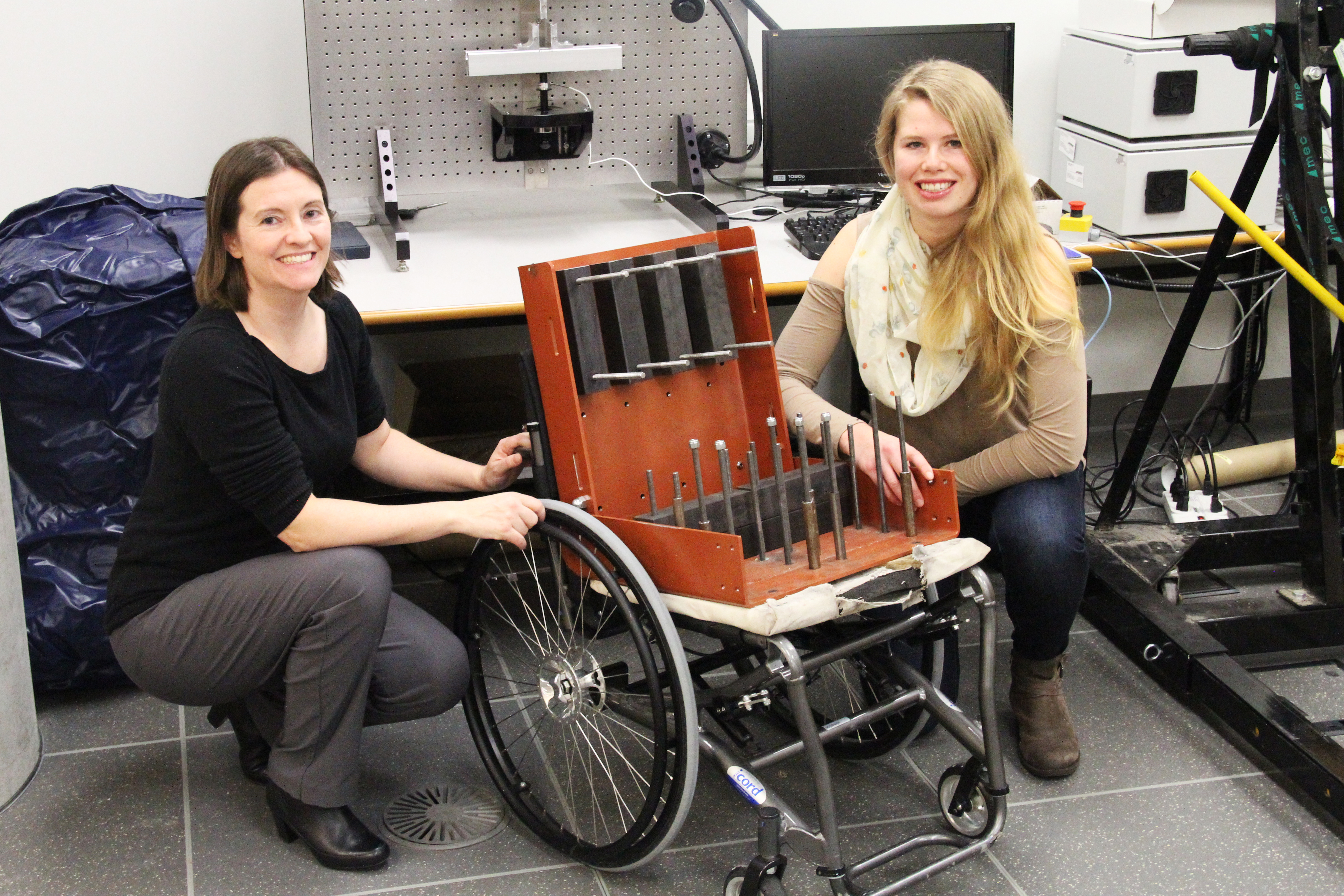 SFU mechatronics professor Carolyn Sparrey (left) and graduate student Louise Thomas (right) pose with the Elevation™ model manual wheelchair with test weights that mimic a seated person.