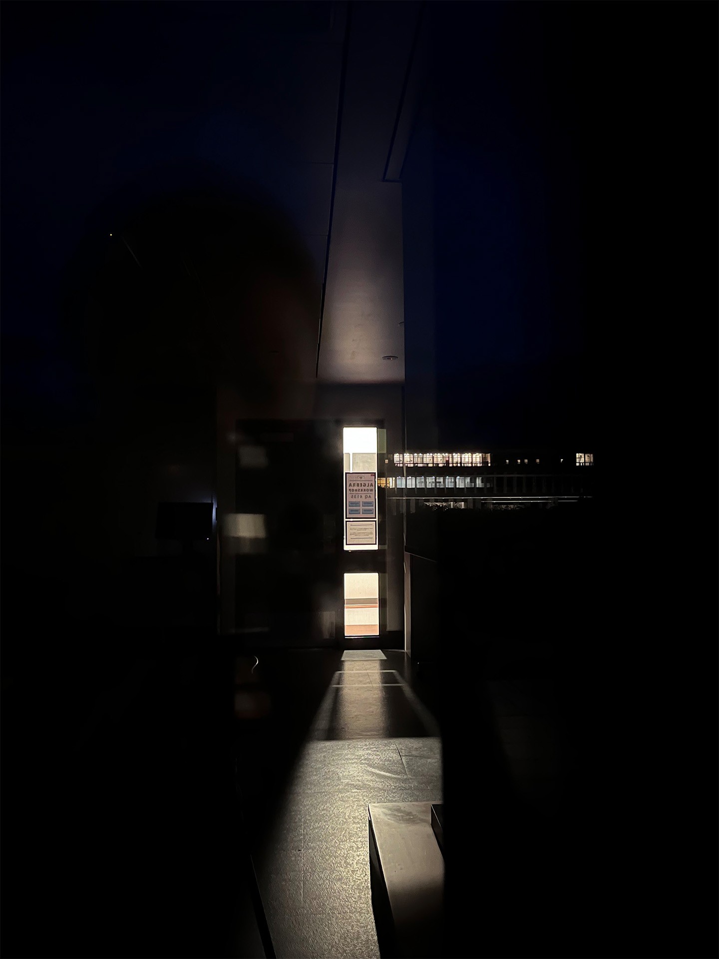 A photo of a dark classroom, the only light coming from the lit hallway beyond the door.