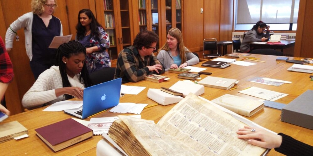 An instructor and five students at SFU Special Collections and Rare Books in the SFU Library, studying books and other printed at materials. 