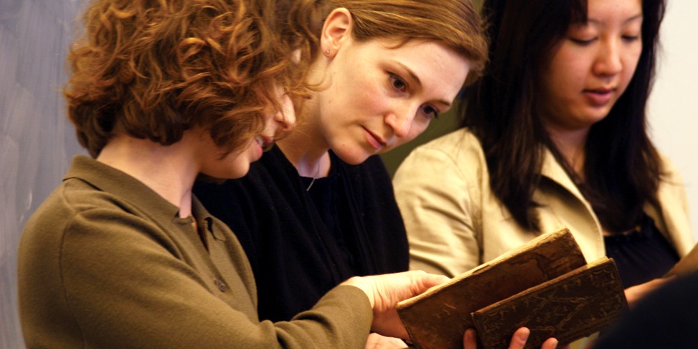 Students examining rare books with a faculty member